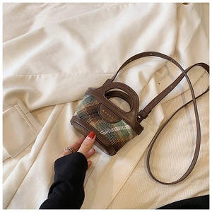 Close-up of mini bucket bag in brown leather and plaid fabric with a top handle