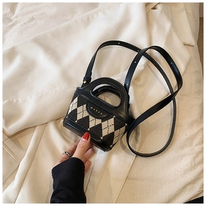 Detailed close-up of a mini quilted bucket bag with gold lettering and leather handle