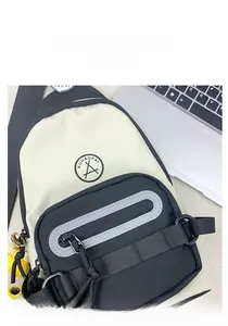 Détail du sac de poitrine en toile avec logo, poche zippée avant et breloque jaune