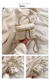 Detail of white quilted mini handbag with gold chain strap and top handle design