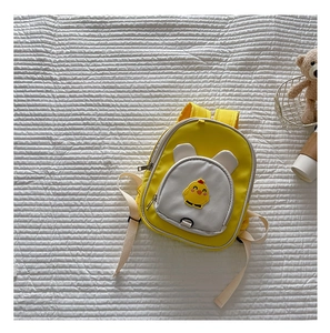 Close-up of yellow cartoon chicken backpack on quilted background with accessories