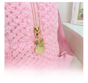 Detail of cute rabbit gold zipper puller on pink plush nursery backpack for toddlers