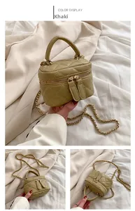 Detailed view of khaki quilted mini chain bag with metallic handle and top zipper