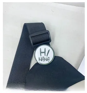 Détail de la bandoulière en nylon noir avec boucle plastique et badge rond HI NANA