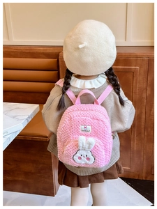Detail of pink plush toddler backpack featuring 3D bunny ornament and soft sherpa texture