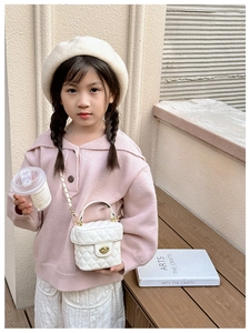 Close-up of white quilted mini bucket bag with gold twist lock on a child model