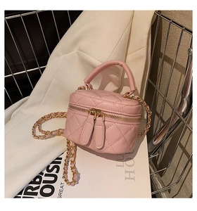 Detailed close-up of pink quilted mini vanity bag with golden chain and zipper