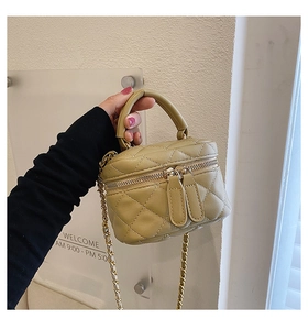 Detailed macro view of khaki quilted mini makeup bag with golden chain and zipper