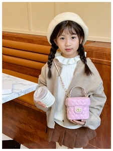 Detail of pink quilted mini bucket bag with gold twist lock and chain strap on child model