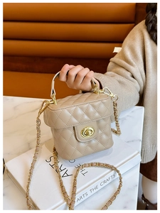 Close-up of quilted beige leather crossbody bag with golden chain strap and twist lock