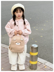Close-up of soft brown teddy bear plush backpack with cute 3D ears and embroidery