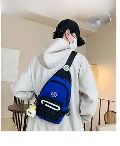 Détail du sac de poitrine en nylon bleu et noir sur modèle avec breloque monstre