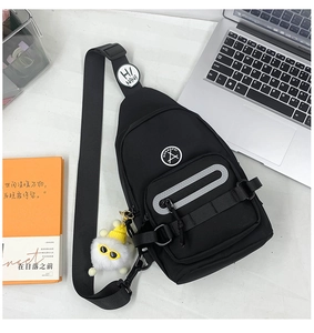 Détail de sac bandoulière noir avec zip réfléchissant et pendentif en peluche doux