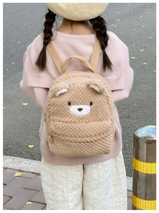 Close-up of soft khaki plush teddy bear backpack featuring embroidered details and 3D ears