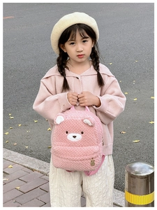 Pink plush kids backpack with bear embroidery and metal rabbit pendant outdoors