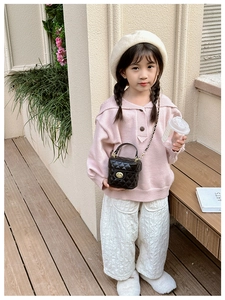 Outdoor shot of a girl wearing a pink knit sweater with a black quilted chain bucket bag