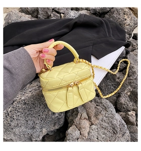 Macro detail of bright yellow quilted mini bag with gold chain and dual zipper
