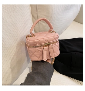 Detailed view of pink quilted mini vanity bag with gold chain and top handle strap
