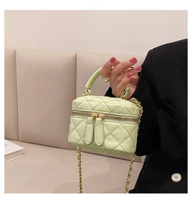 Detail of mint green quilted mini bag with gold chain strap and dual zippers
