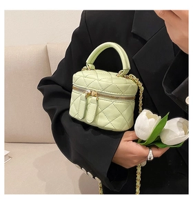Detail of light green quilted mini vanity case with top handle and gold chain strap