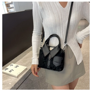 Detail of creative shirt-shaped black bucket bag with lapel and button accents