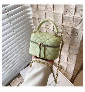 Detail of light green quilted mini vanity bag with gold chain strap and top handle
