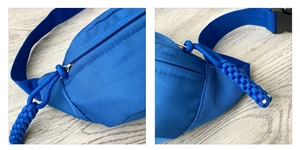 Detail of royal blue nylon fanny pack showing twill texture and woven zipper puller