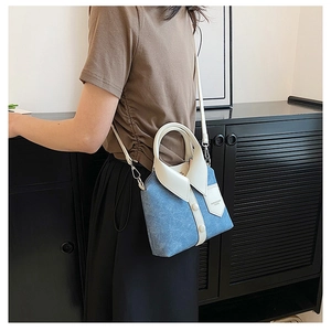 Blue denim shirt-style crossbody bag with white handles shown on model's side