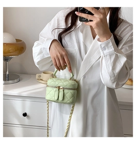 Detail of mint green quilted mini vanity bag with gold chain strap and dual zippers