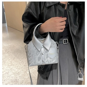Detailed close-up of a silver shirt-shaped bucket bag with buttons and textured finish