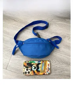 Close-up of blue nylon waist bag with woven zipper pull and adjustable shoulder strap