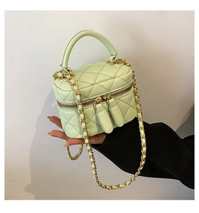 Detail of mint green quilted mini vanity bag with golden chain strap and top handle