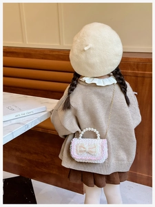 Detail of sequin kids handbag featuring pearl bow and metallic chain strap shown with model