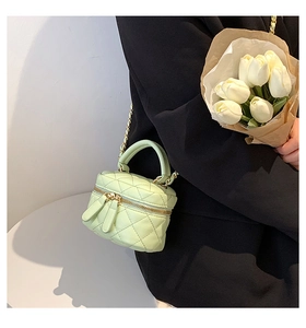 Detail of light green quilted mini crossbody bag with metal chain strap and top handle