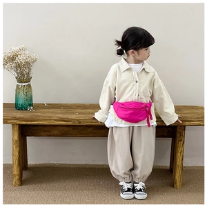 Close-up of a vibrant pink canvas kids fanny pack worn by a model in a minimal setting