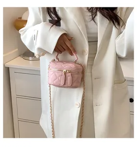 Close-up of pink quilted mini makeup bag with chain strap and gold hardware accents