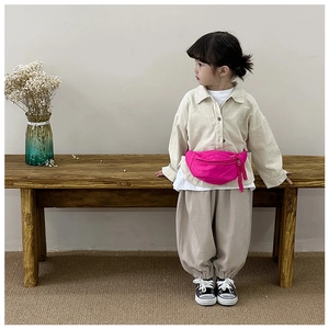 Close-up of rose pink kid's chest bag showing textured fabric and zipper details on model