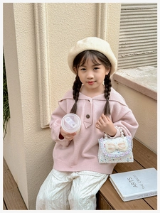 Detail of pink knitted girl's top with white sequin bow bag and chic pearl handle