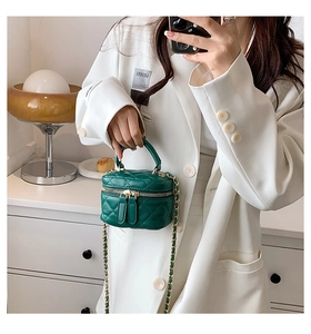 Detail of green quilted mini vanity bag with gold chain strap in a lifestyle setting