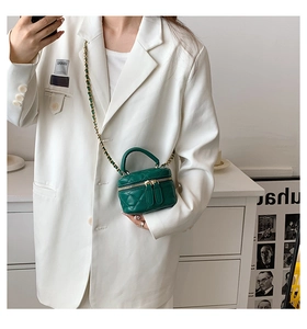 Detail of green quilted leather mini vanity bag with gold chain strap worn cross-body