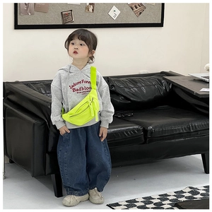 Detail of neon yellow kids fanny pack with adjustable black strap on a young model