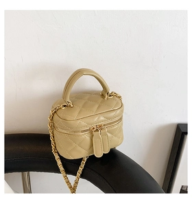 Detail of beige quilted mini cosmetic bag with top handle and gold chain strap