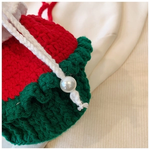 Détail de pochette de Noël au crochet rouge et vert avec cordon et perle de décoration