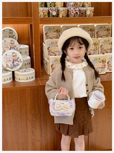 Detail of colorful tweed child handbag with pearl handle and bow on autumn outfit