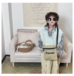 Kid's khaki canvas crossbody bag with Freedom letter print shown in home setting