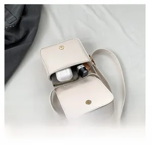 Internal view of cream small crossbody bag showing storage capacity for lipstick and earbuds
