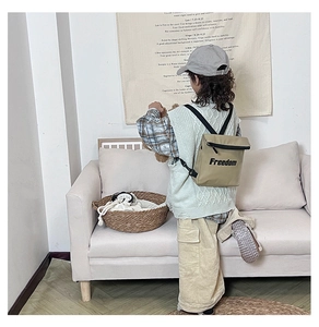 Kids khaki canvas backpack with Freedom letter print shown on model in cozy home setting