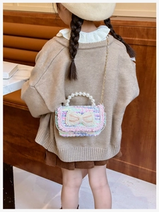 Rear view of girl wearing a colorful woven mini bag with pearl bow and gold chain strap