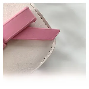 Detailed close-up of white lychee leather texture and pink bow on small square bag