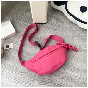 Detail view of pink canvas crossbody bag with woven zipper pull and adjustable strap
